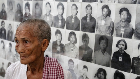 Një i mbijetuar i regjimit të Kmerëve të Kuq përpara portreteve të viktimave në Tuol Sleng